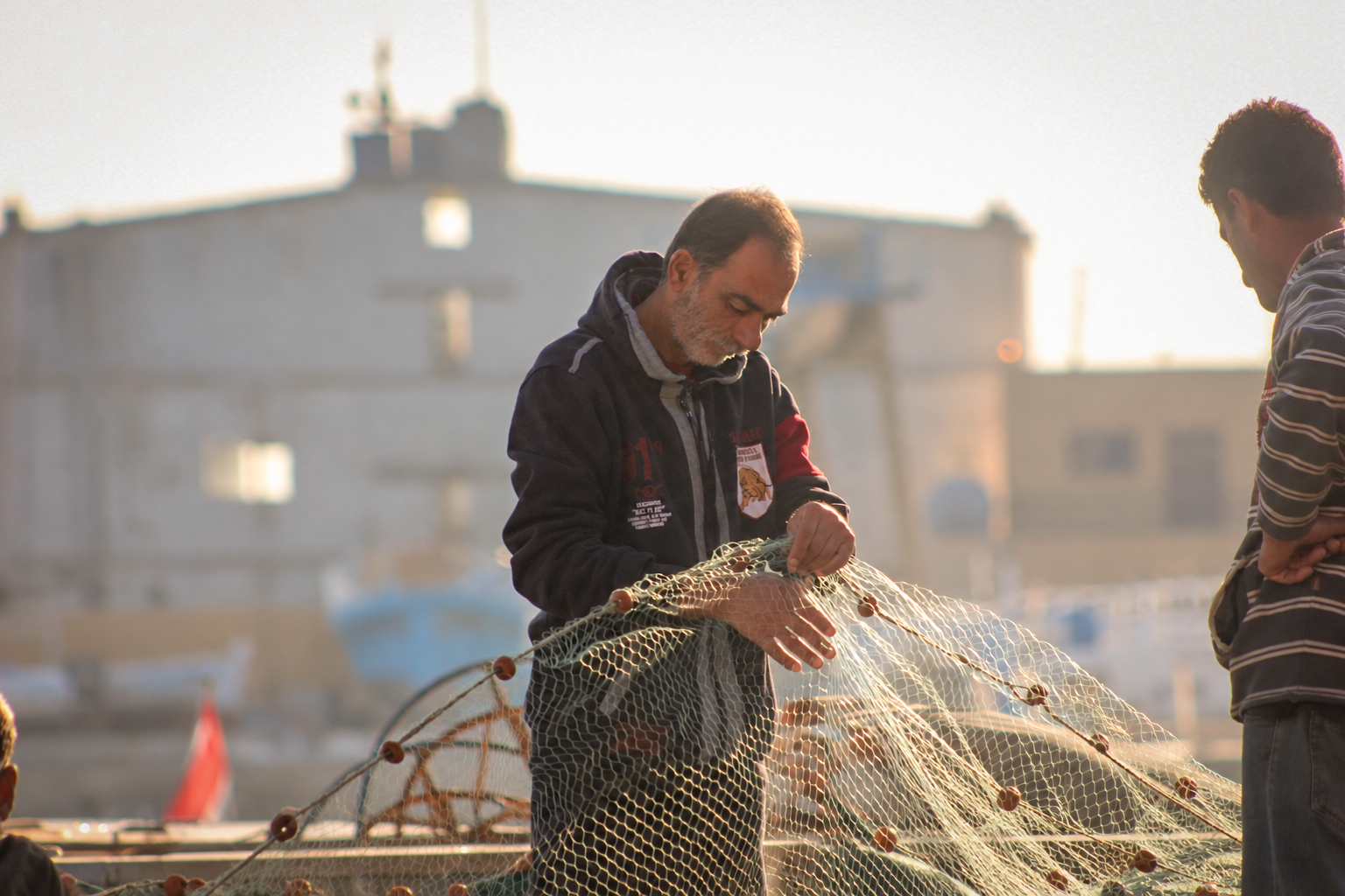 Two fishermen working a net at the harbour