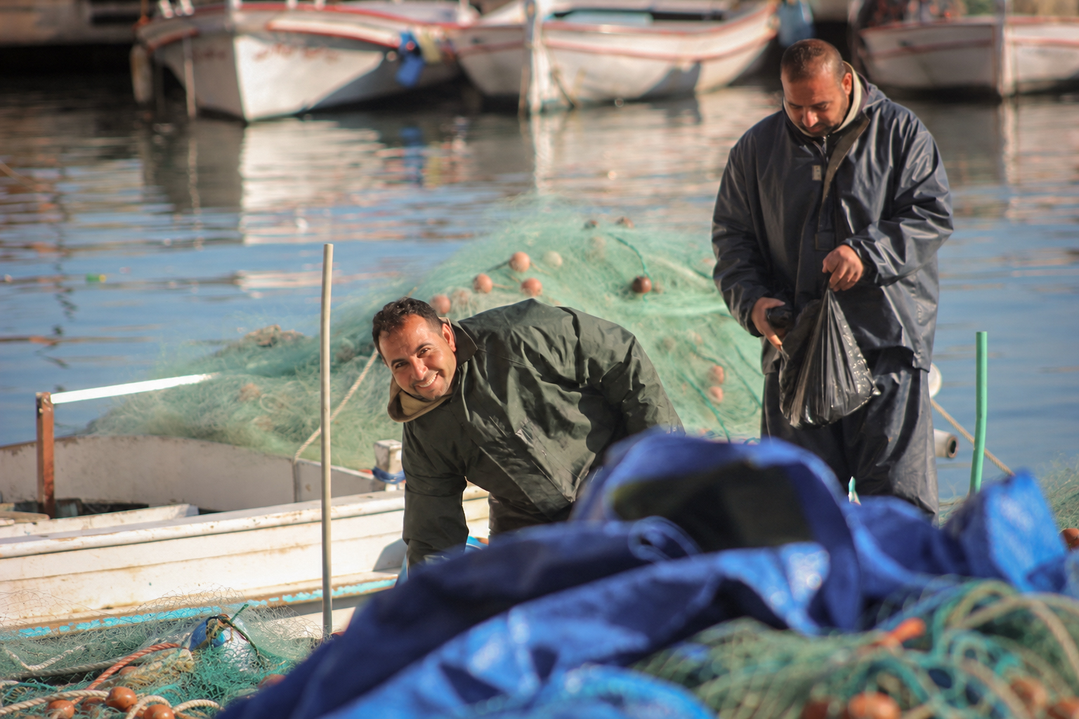 Two fishermen sorting nets and gear on a boat