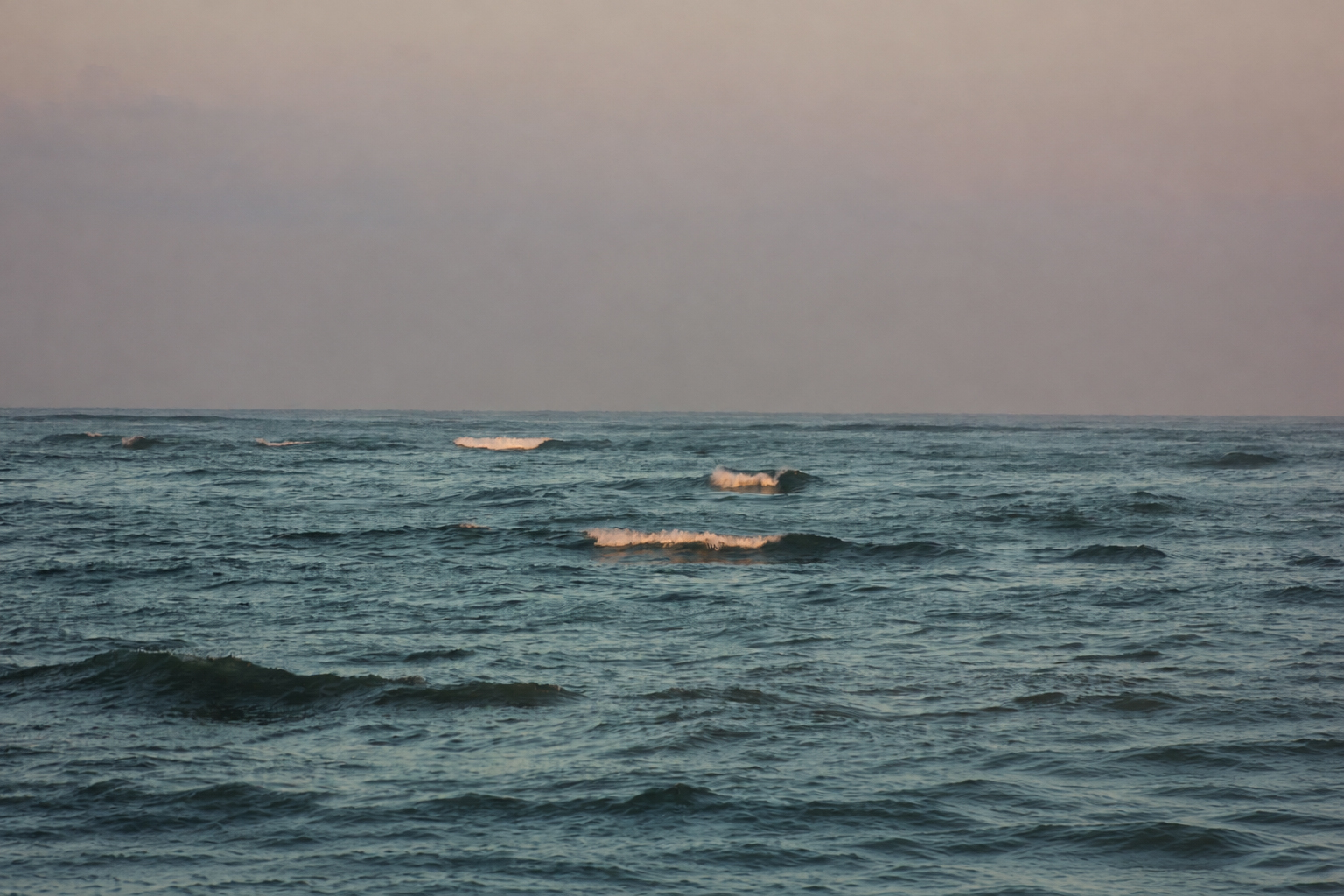 Small boats far out at sea at dawn