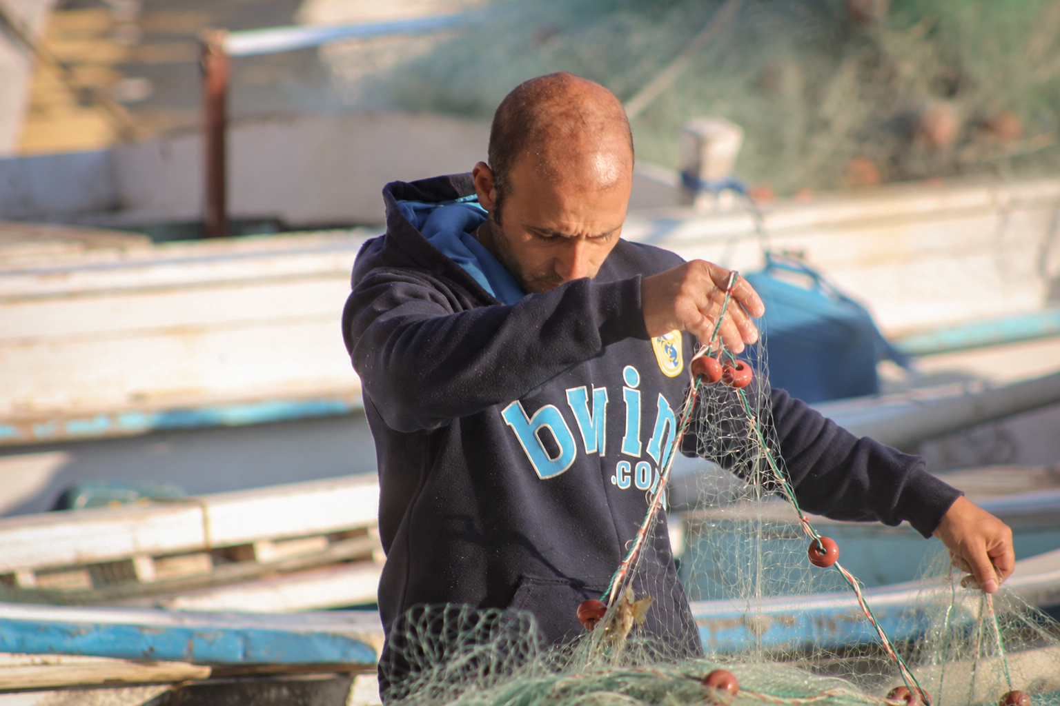 A fisherman mending a net on the quay