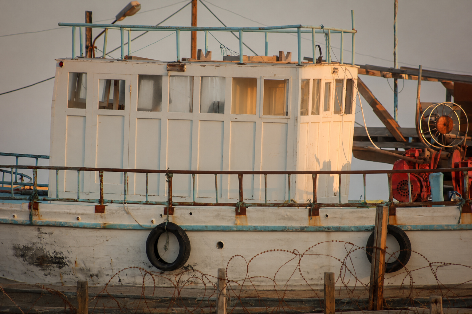 A white fishing boat and its wheelhouse, tied up at the quay