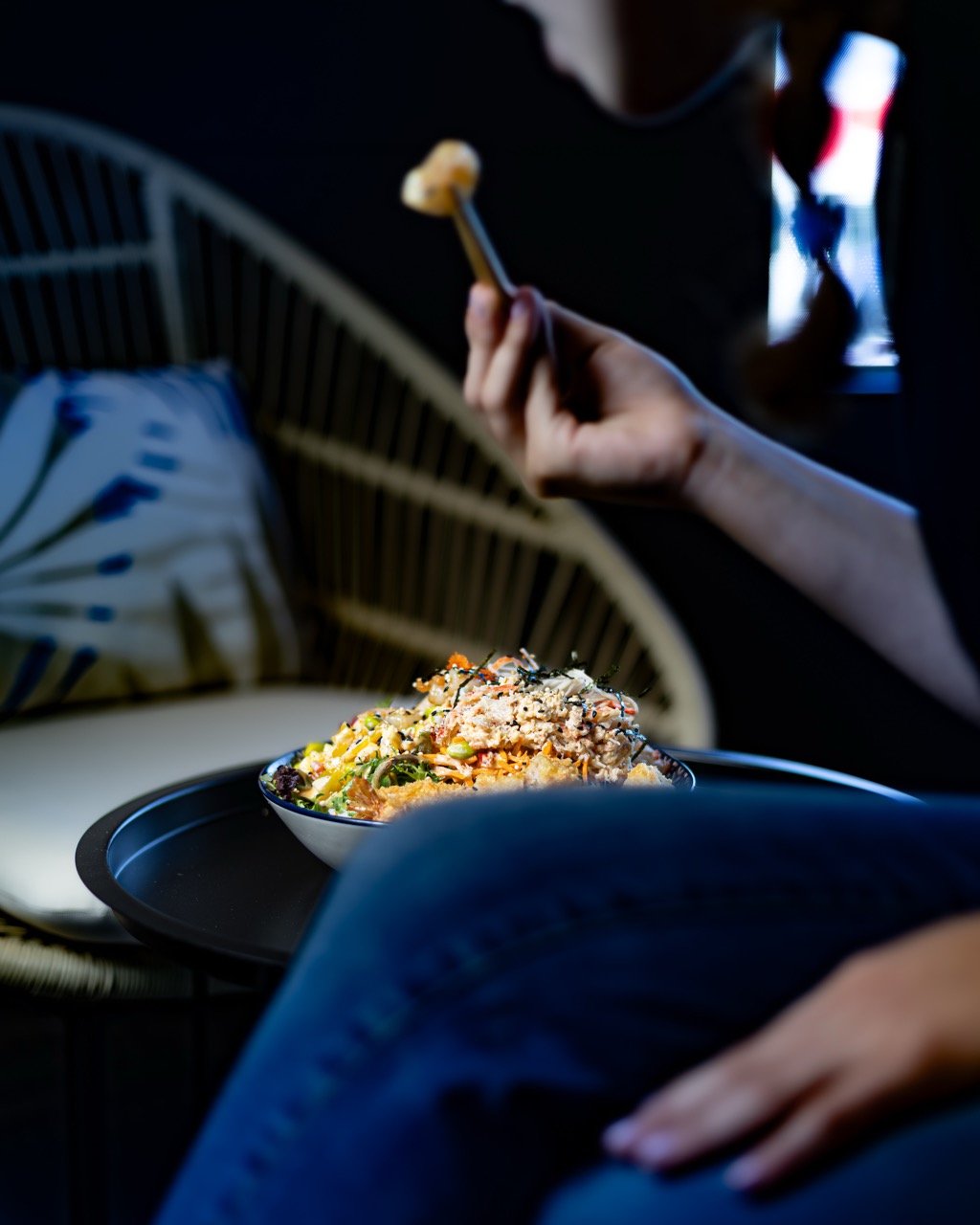 Person holding a bowl of fusion food with fresh ingredients