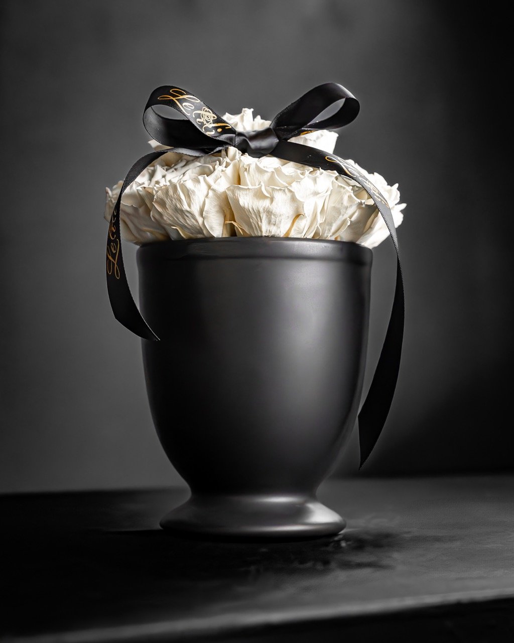 Still Life Photo of white flowers in a dark vase.