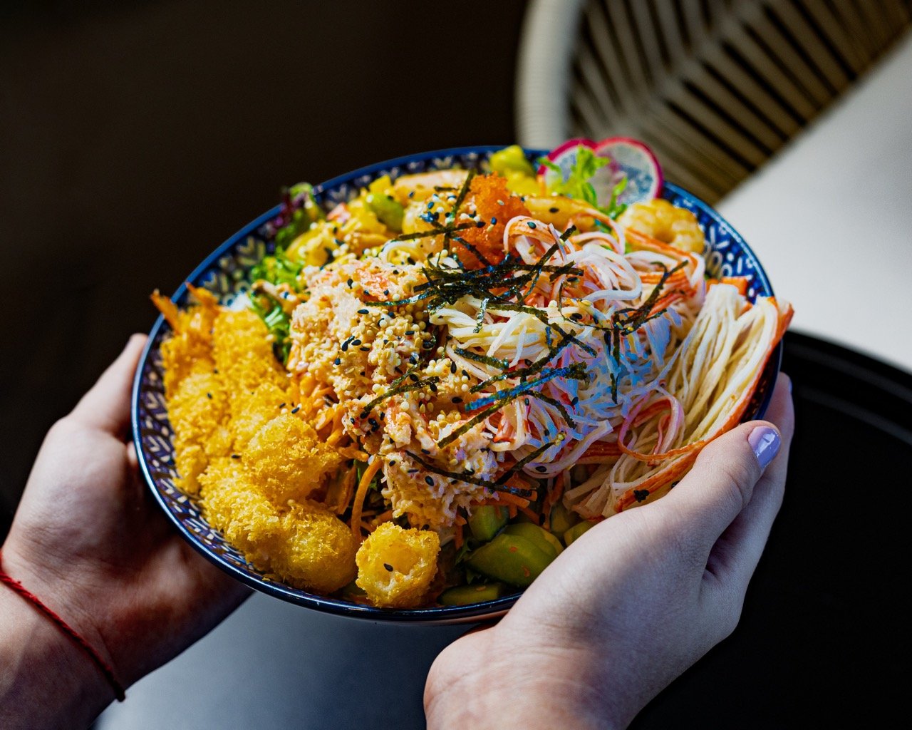 A person happily eating from a colorful fusion bowl.
