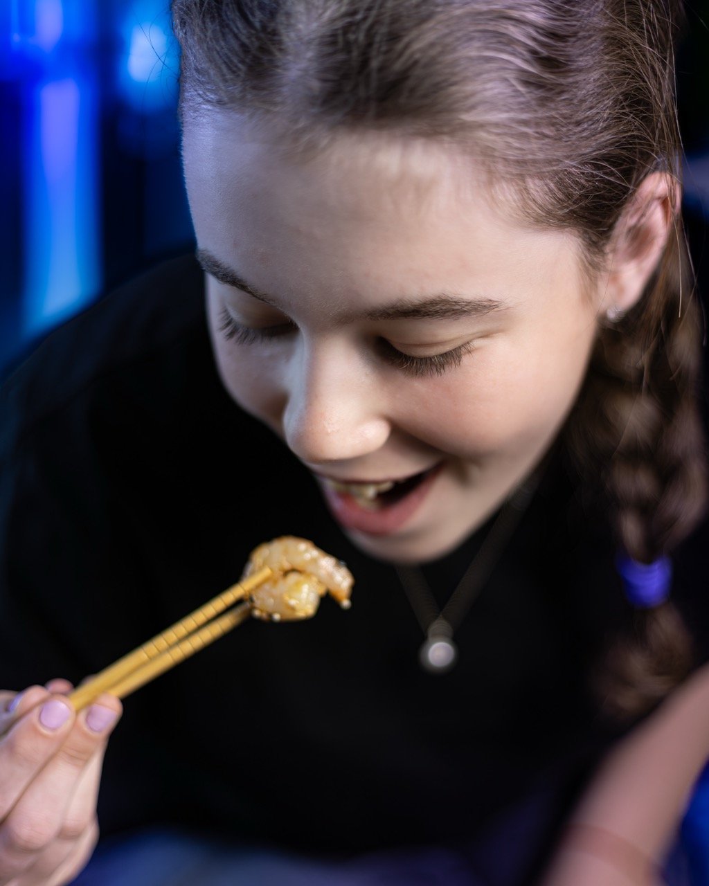 A powerful hero shot of a person enjoying a bowl of fusion cuisine with chopsticks.